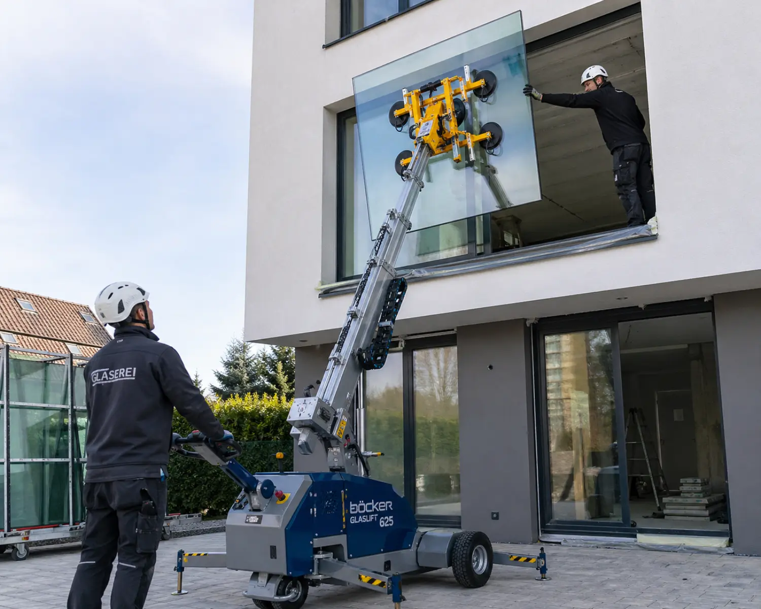 Glaser verwendet einen mobilen Akku-Vakuumsauger, um eine große Glasscheibe sicher anzuheben.