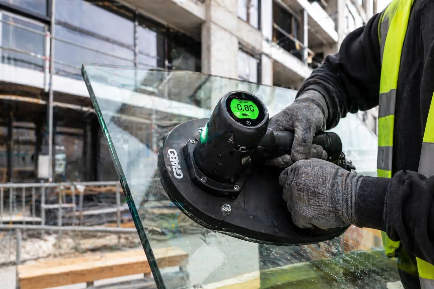 Ein kompakter Glaslift mit Sauganlage positioniert eine schwere Fensterscheibe präzise in einem Rohbau.