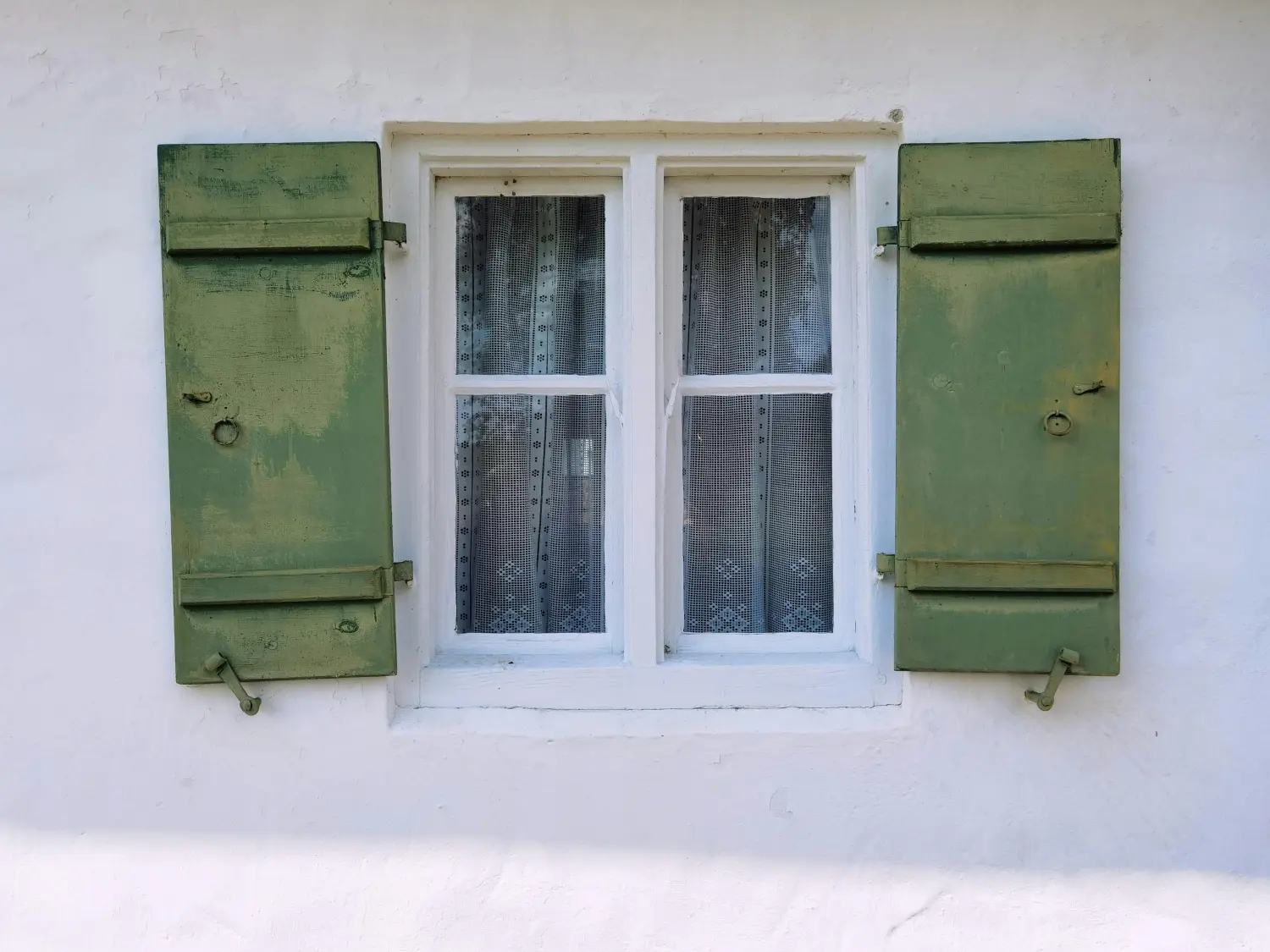Ein altes, verwittertes Fenster, dessen Beschläge deutliche Verschleißspuren aufweisen und von einem Experten geprüft werden müssen.