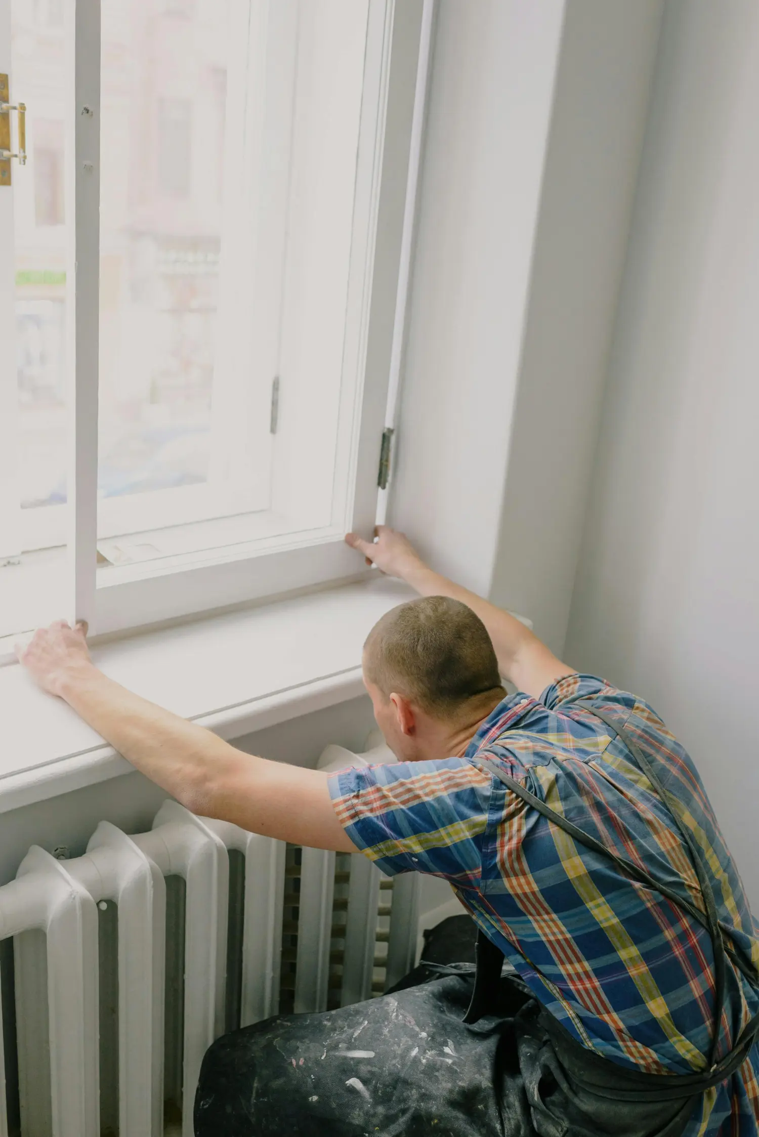 Ein Handwerker rüstet ein Fenster mit einem neuen Sicherheitsbeschlag nach.