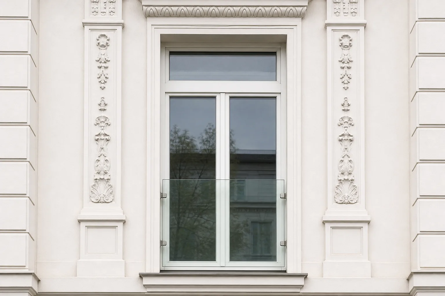 Französischer Balkon mit raumhohem Glasgeländer an einer Altbaufassade