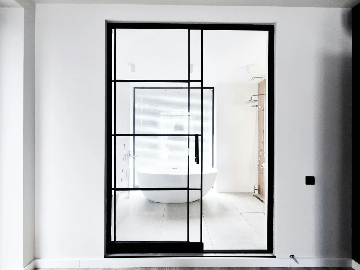 Moderne Glasschiebetür, die platzsparend an der Wand entlang läuft.