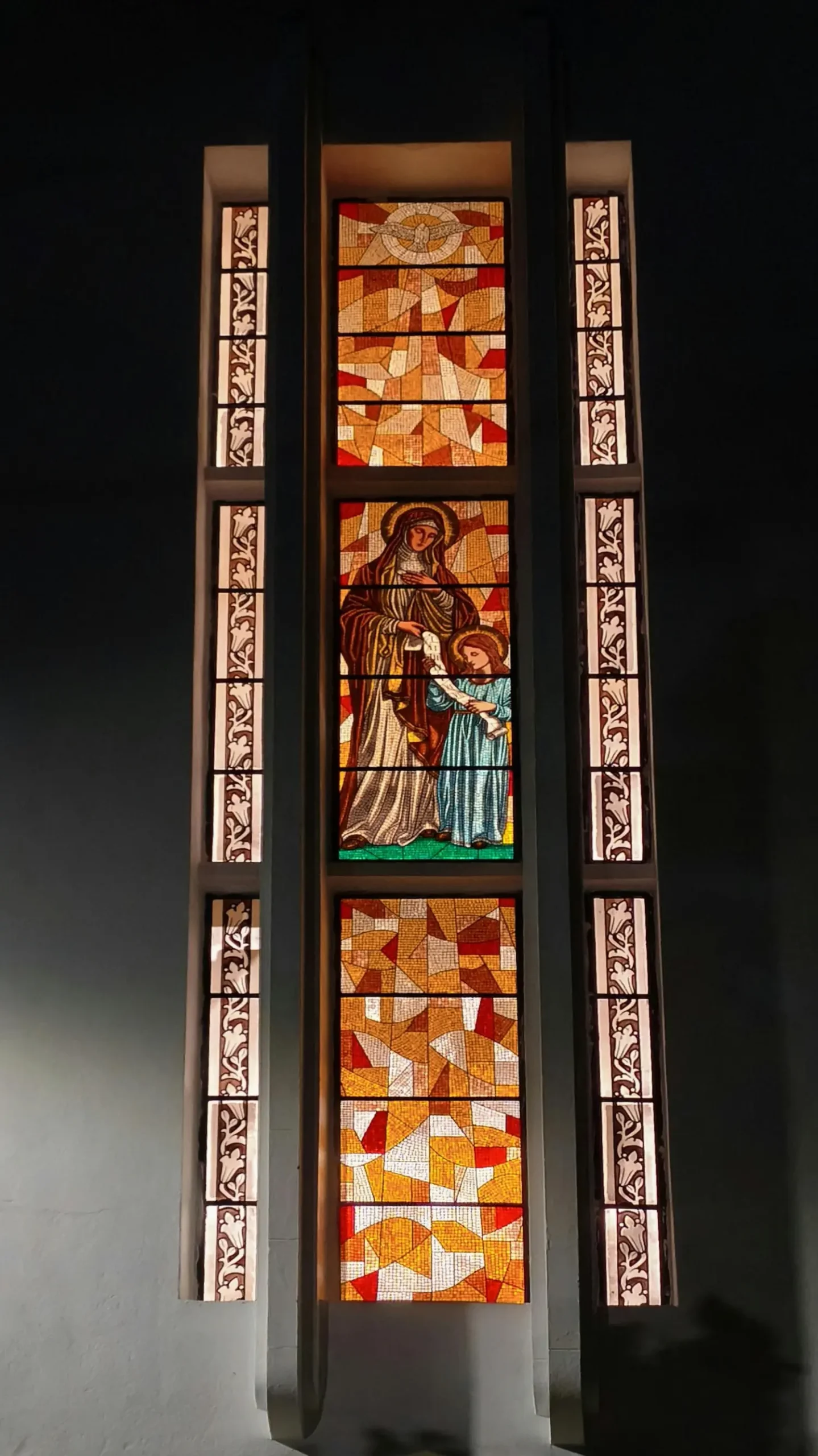Ein saniertes, gotisches Maßwerkfenster leuchtet in einer alten Kirchenmauer.
