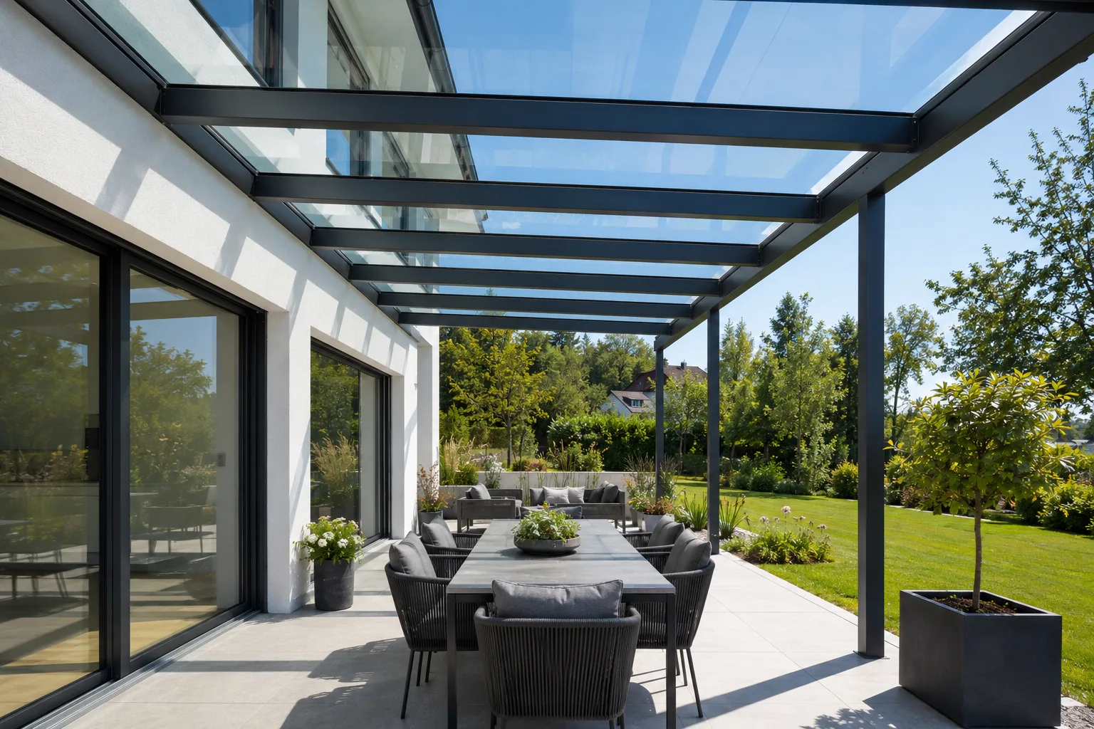 Glas-Terrassenüberdachung als zuverlässiger Regenschutz über einer Sitzecke.